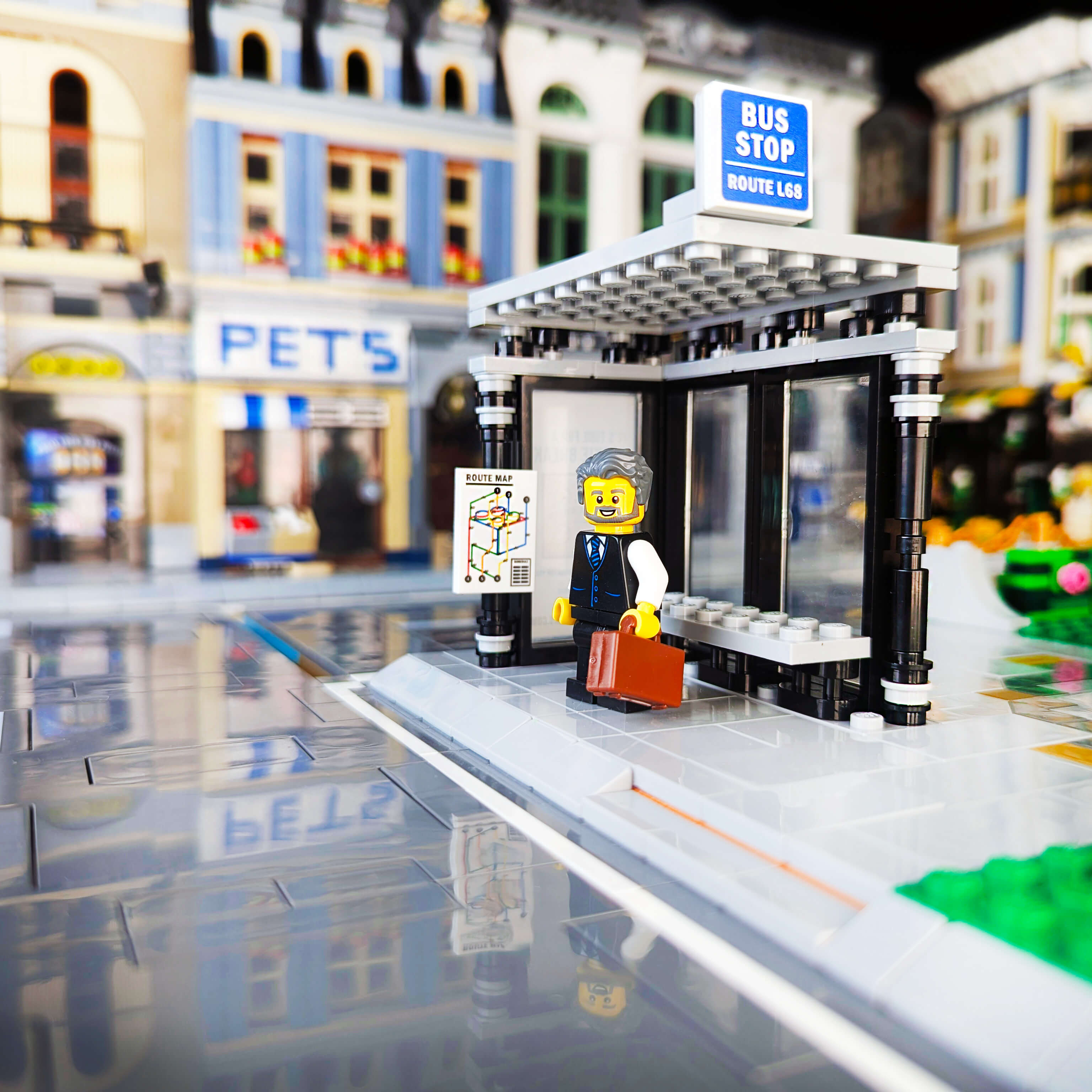 LEGO bus stop with a character and a bottle, set against a blurred city street background.